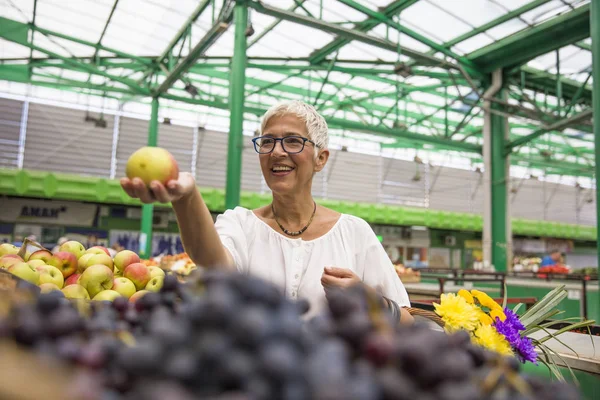 快乐的老年妇女在市场上购买苹果 — 图库照片