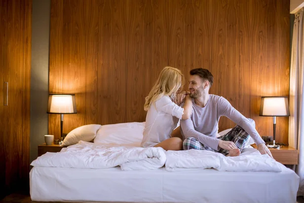 Yatak odasındaki yatakta oturan sevgi dolu ve sarılan genç çift.