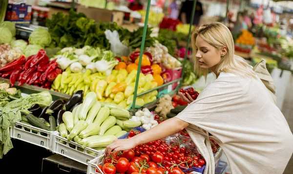 市場で野菜を買うのはかなり若い女性で表示します — ストック写真