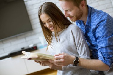 Katta oturan bir kitapla genç Çift