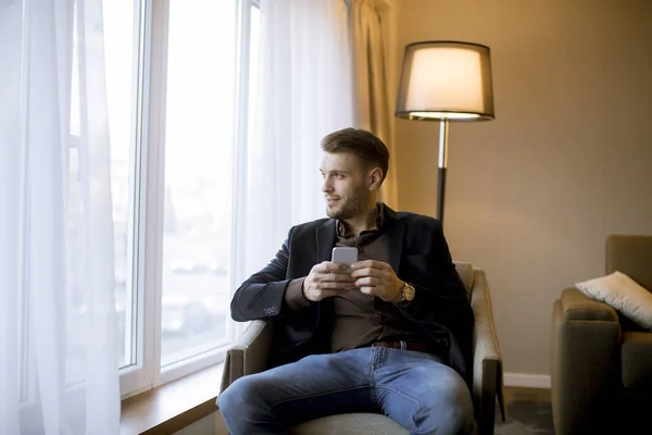Όμορφος Νέος Άνδρας Που Χρησιμοποιούν Κινητό Τηλέφωνο Στο Δωμάτιο Από — Φωτογραφία Αρχείου