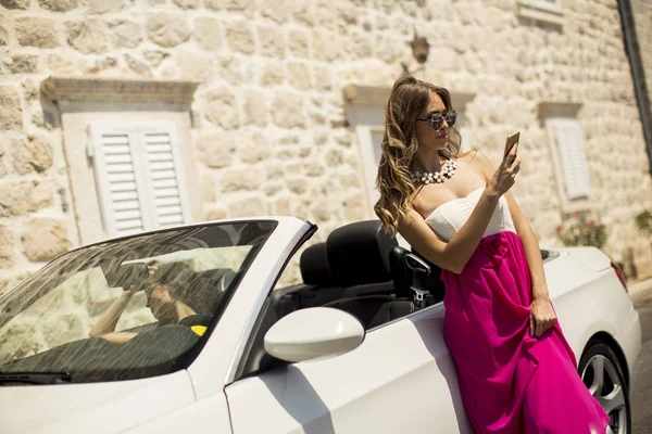 Νεαρή Γυναίκα Χρήση Κινητού Και Στέκεται Καμπριολέ Αυτοκίνητο Στην Καυτή — Φωτογραφία Αρχείου