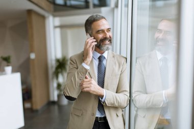 Cep telefonuyla ofiste yakışıklı olgun işadamı
