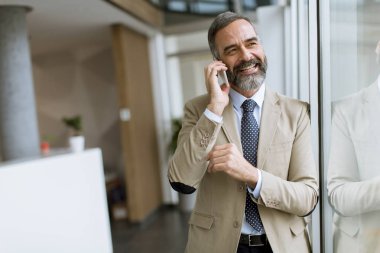 Cep telefonuyla ofiste yakışıklı olgun işadamı