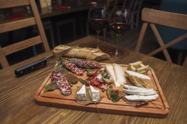 Peynir, sosis ve meze olarak kırmızı şarap ahşap masa servis