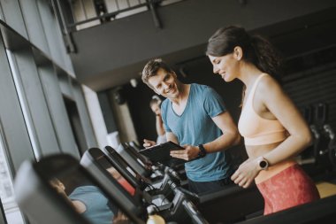 Genç kadın ile Trainer çalışma dışarı üzerinde koşu bandı içinde spor salonu
