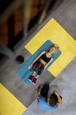 Sportif kadın spor salonunda onun kişisel eğitmen yardımıyla egzersizleri yapıyor üst görünüm