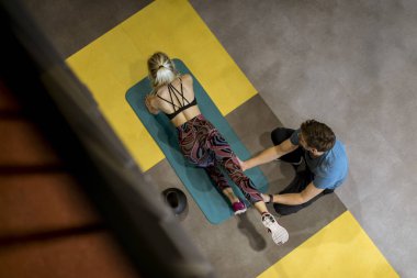 Sportif kadın spor salonunda onun kişisel eğitmen yardımıyla egzersizleri yapıyor üst görünüm