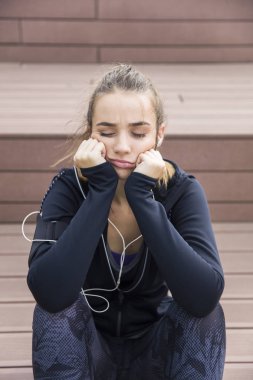 Sinirli ve yorgun genç sportif kadın merdivenlerden açık oturma