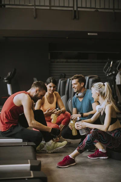 在运动服装上的年轻人在健身后在健身房休息时一起谈笑风生 — 图库照片