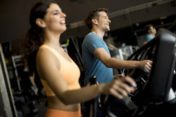 Close up view at woman and man on elliptical stepper trainer exercising in gym