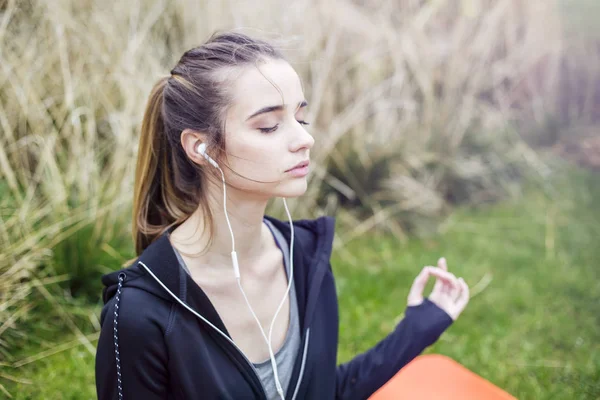 Genç Kadın Müzik Dinlemek Çim Üzerinde Yoga Zen Poz Yapıyor — Stok fotoğraf