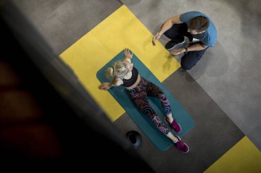 Sportif kadın spor salonunda onun kişisel eğitmen yardımıyla egzersizleri yapıyor üst görünüm