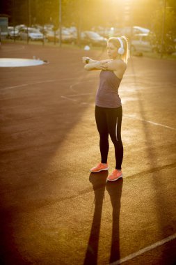 İnce uygun sarışın kadın egzersiz daha önce sahada germe yapıyor