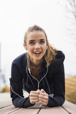 Sportif genç kadın, açık havada karın kasları ve triceps üzerinde çalışan tahta egzersiz yapıyor