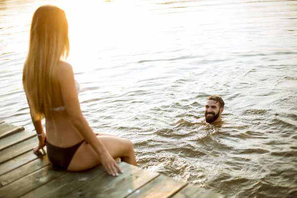 Счастливая Молодая Пара Наслаждается Пока Женщина Сидит Пирсе Мужчина Плавает — стоковое фото