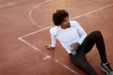 Basketbol sahasında oturan kıvırcık saçlı çekici siyah adam yakın