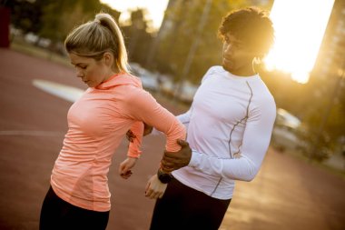 Afro-Amerikan kişisel antrenör açık havada silah için egzersiz çalışan kadın yardım