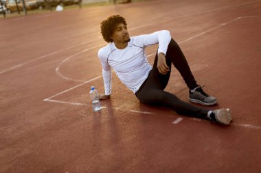 Basketbol sahasında oturan kıvırcık saçlı çekici siyah adam yakın
