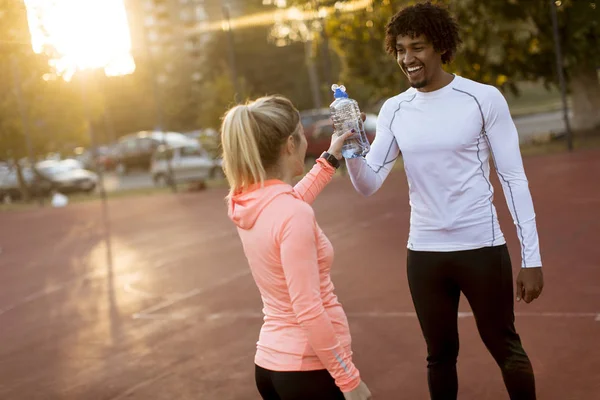 Multiracial couple of young runners resting after training