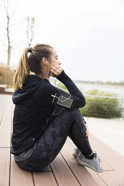 Frustrated and tired young sporty woman sitting outdoor on stairs