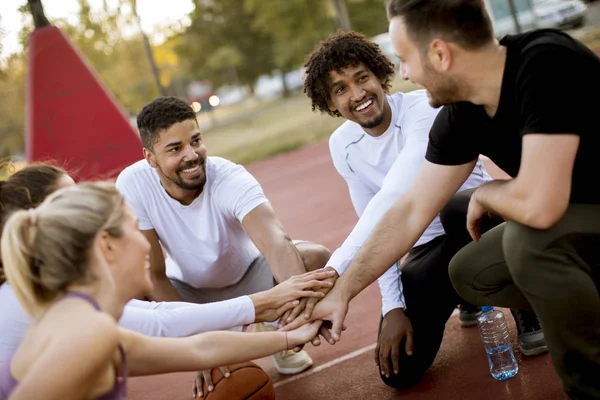 Multiethnic group of young basketball players resting on court together