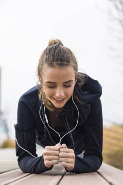 Sportif genç kadın, açık havada karın kasları ve triceps üzerinde çalışan tahta egzersiz yapıyor