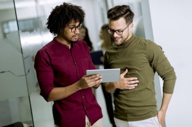 Ofiste dijital tablet kullanan çok ırklı genç iş ortakları