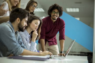 Yaratıcı ofiste çalışan ve iletişim kuran çok ırklı genç iş adamları grubu