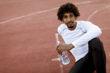 Basketbol sahasında oturan kıvırcık saçlı çekici siyah adam yakın