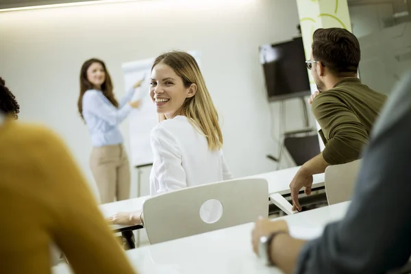 小さなオフィスでのワークショップ中に学生とビジネスプランについて話す創造的なポジティブな女性リーダー — ストック写真