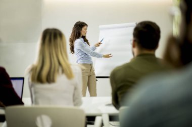Yaratıcı pozitif kadın lider küçük ofiste atölye sırasında öğrencilerle iş planı hakkında konuşurken