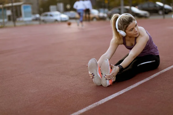 Dışarıdaki Sahada Isınma Egzersizleri Yapan Bacaklarını Açan Genç Bir Kadın — Stok fotoğraf