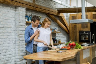 Güzel neşeli genç çift birlikte akşam yemeği pişirme ve rustik mutfakta eğlenmek