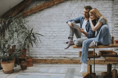 Güzel genç çift bir dijital tablet kullanıyor ve evde mutfakta gülümsüyor