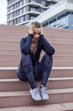 Endişeli genç bayan merdivenlerde oturuyor.