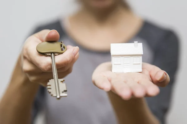 Female holding small house model and keys, real estate concept