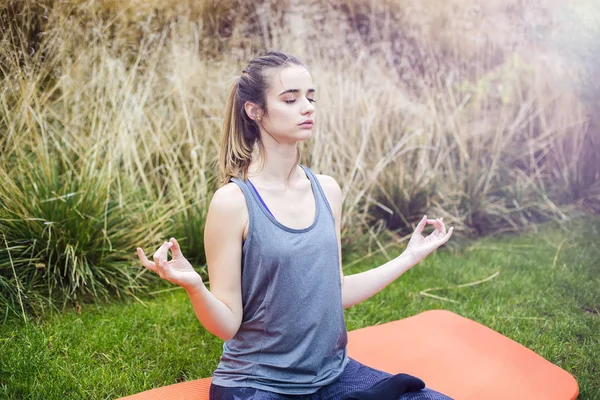 Genç kadın yoga yapıyor ve lotus pozisyonunda meditasyon yapıyor. — Stok fotoğraf