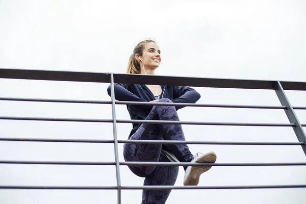 Young woman in sportswear resting on the fence during the mornin — 스톡 사진