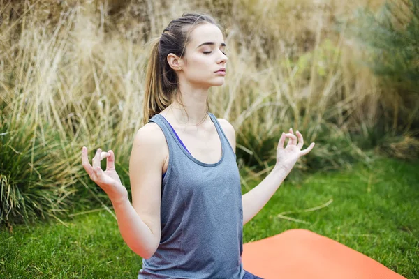 Genç kadın yoga yapıyor ve lotus pozisyonunda meditasyon yapıyor. — Stok fotoğraf