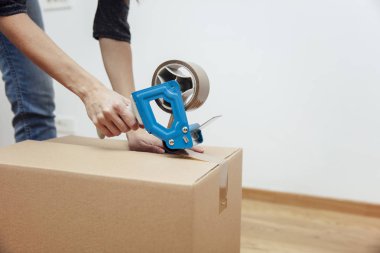 Bir nakliye kutusu mühür için bir bant dispenseri kullanarak mans ellerin closeup