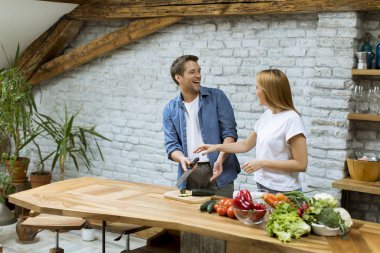 Güzel neşeli genç çift birlikte akşam yemeği pişirme ve rustik mutfakta eğlenmek