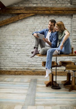 Güzel genç çift bir dijital tablet kullanıyor ve evde mutfakta gülümsüyor