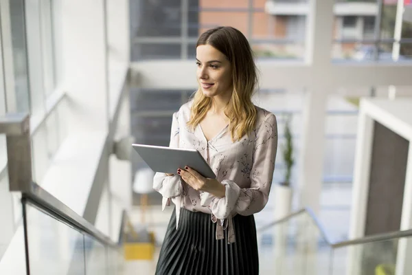 Empresária atraente usando um tablet digital enquanto está de pé o — Fotografia de Stock
