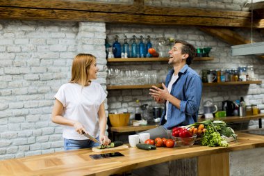 Güzel neşeli genç çift birlikte akşam yemeği pişirme ve rustik mutfakta eğlenmek