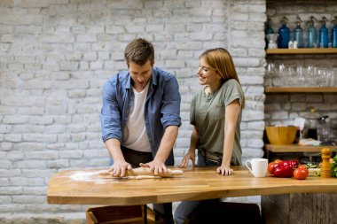 Genç bir çift, kırsal mutfakta pizza pişiriyor.