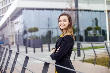 Şirket binası önünde açık havada duran genç iş kadınının portresi