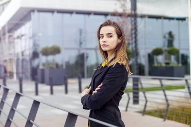 Şirket binası önünde açık havada duran genç iş kadınının portresi