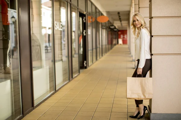 美丽的女人与纸购物袋站在商店 — 图库照片
