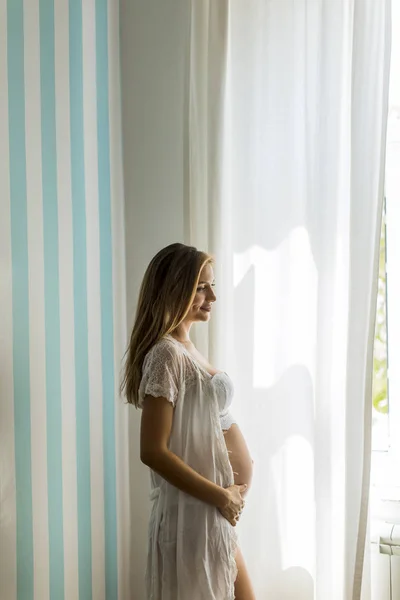 Красивая Молодая Беременная Женщина Стоит Голубой Полосатой Стены Комнате Дневном — стоковое фото